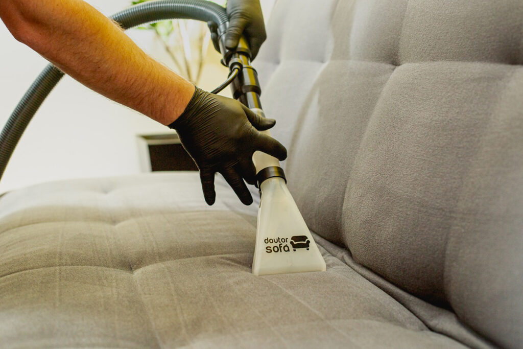 Extraction nozzle with the Doctor Sofa logo moving over the seat of a grey sofa.