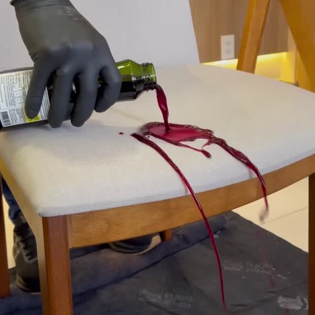 Doctor Sofa technician wearing a mask, goggles, gloves and foot protection, cleaning the cushions of a light-coloured sofa.